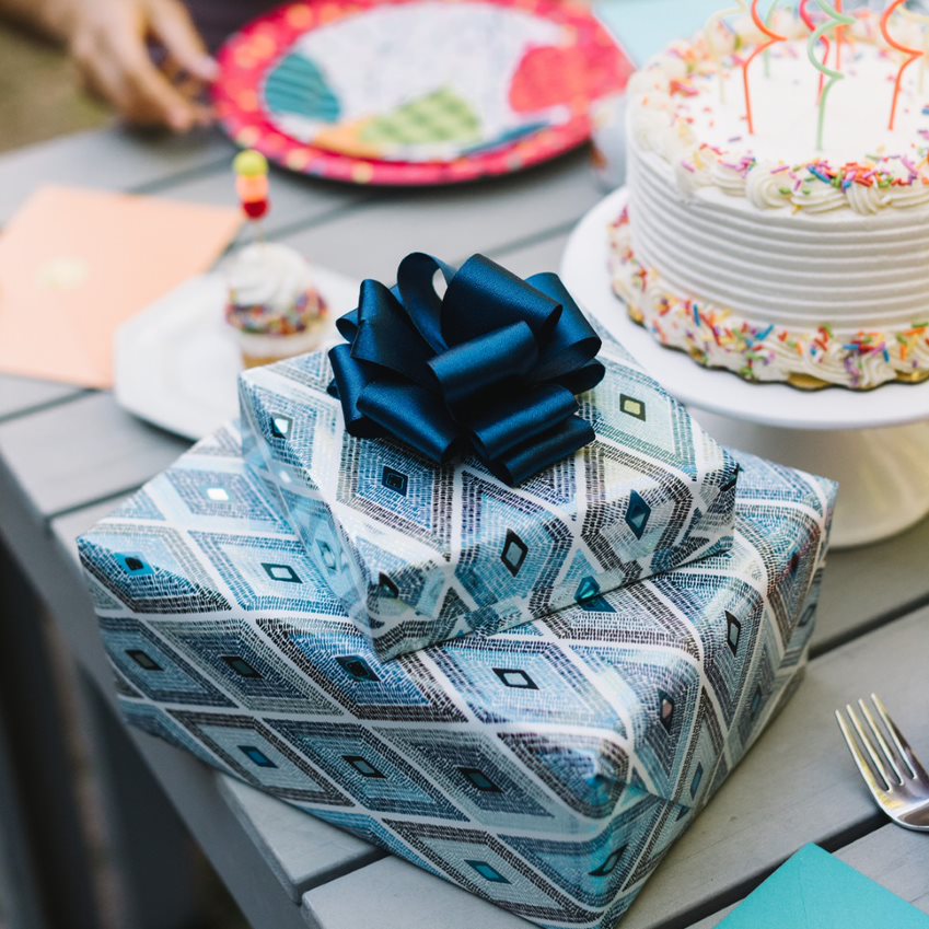 Teal and silver wrapped presents on table with cake and candles