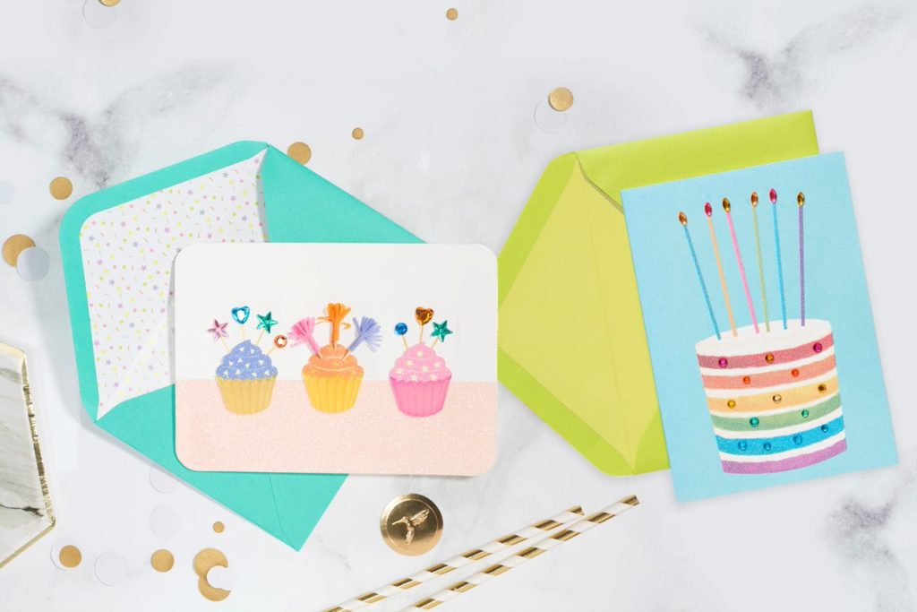 Cupcakes birthday greeting card and rainbow birthday greeting cards on marble table