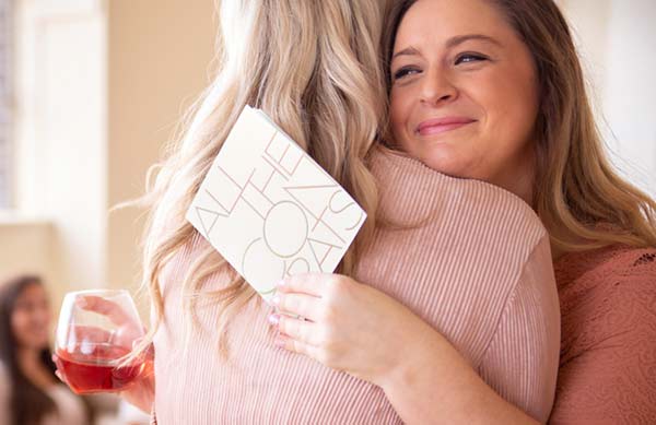 Women hugging holding all the congrats card